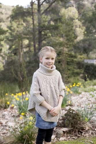 Smiling girl standing in front of bushland - Australian Stock Image