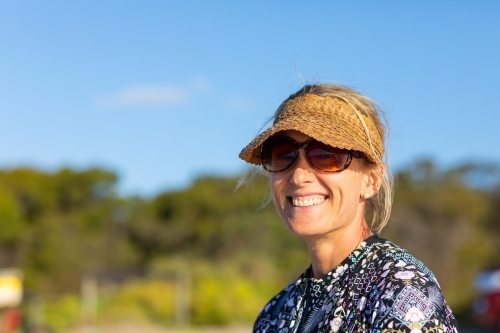 smiling lady with sun visor and sunglasses - Australian Stock Image