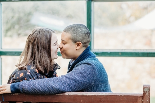 smiling lgbtqi couple about to kiss while sitting on a bench