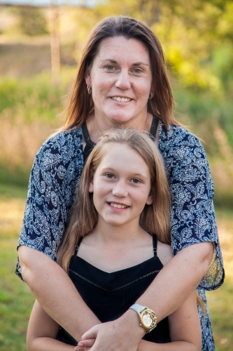 Smiling mother and daughter portrait mother hugging tween daughter - Australian Stock Image