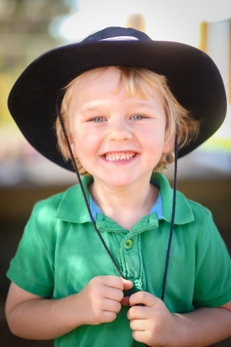 Smiling preschool boy wearing wide brim hat outdoors - Australian Stock Image