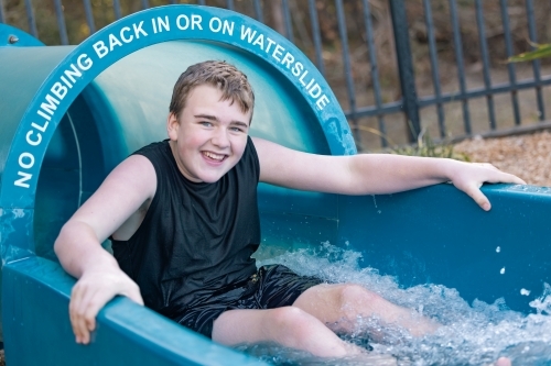 Smiling teen boy on waterslide - Australian Stock Image