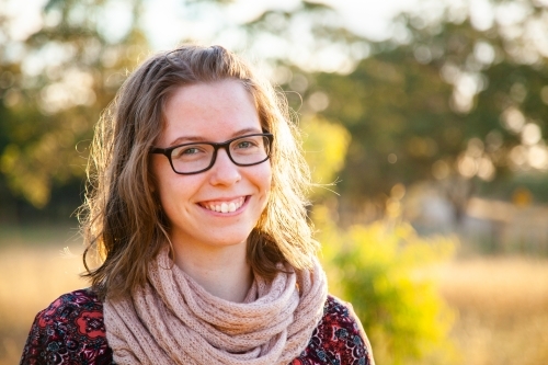 Smiling teenager with scarf outside in natural surroundings - Australian Stock Image