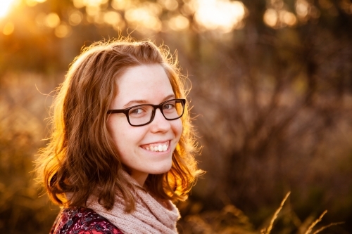 Smiling teenager with scarf outside in natural surroundings - Australian Stock Image