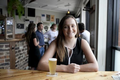 Smiling woman having a drink at local craft beer bar