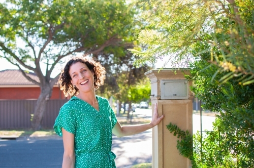 Smiling woman standing by mailbox at home