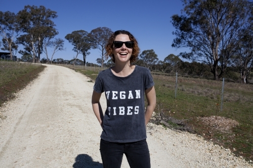 Smiling woman wearing vegan slogan t-shirt standing on rural dirt road