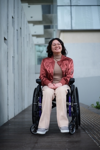 Smiling woman with a disability sitting in a wheelchair outside - Australian Stock Image