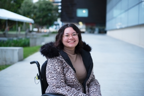Smiling woman with a disability sitting in a wheelchair outside