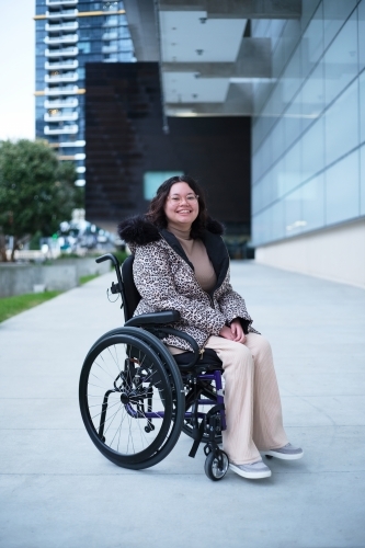 Smiling woman with a disability sitting in a wheelchair outside in a city
