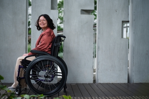 Smiling woman with a disability sitting in a wheelchair outside in urban setting