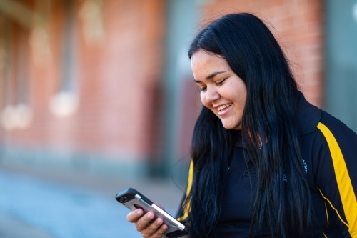 smiling young lady looking at smartphone - Australian Stock Image