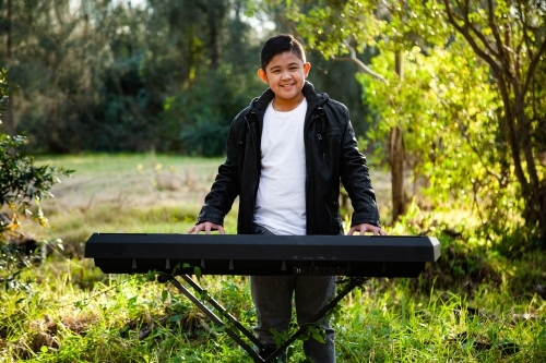 Smiling young person playing keyboard outside - Australian Stock Image