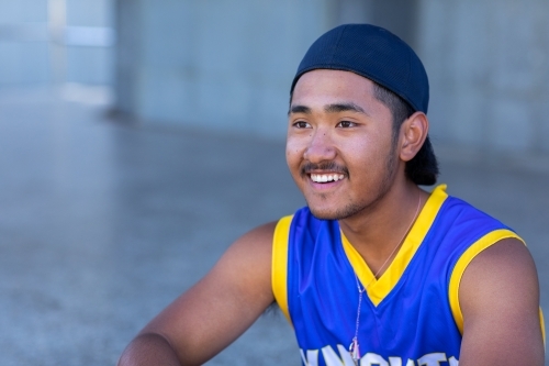 smiling youth wearing baseball shirt and cap on backwards - Australian Stock Image