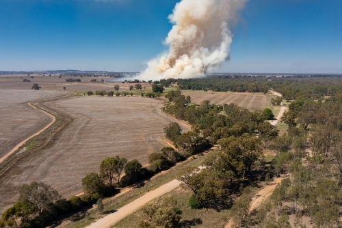 Smoke billowing into the air from a bush fire over dry farmland
