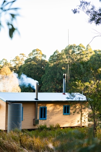 Smoke coming from chimney in cabin in clearing - Australian Stock Image