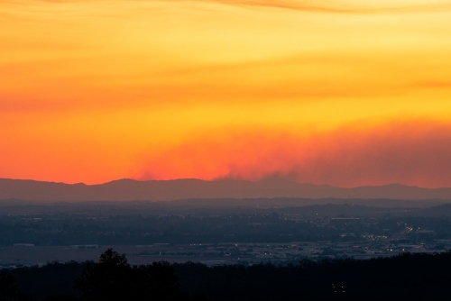 Smoke from fires on the ranges in an orange sunset - Australian Stock Image