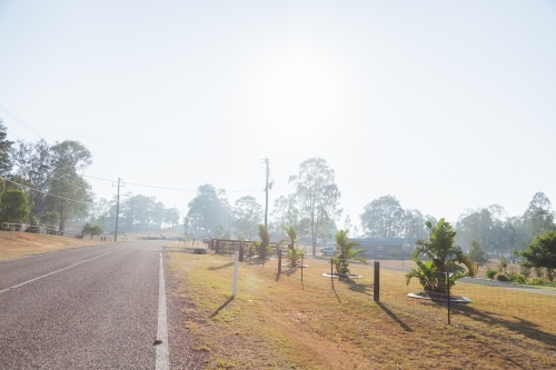 Smoke haze over road and properties at the edge of a town - Australian Stock Image