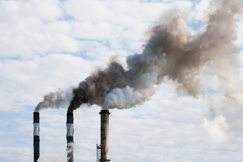 Smoke pouring from smokestacks at a rural sugar refinery - Australian Stock Image