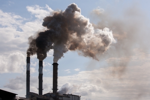 Smoke pouring from smokestacks at a rural sugar refinery - Australian Stock Image