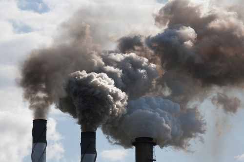 Smoke pouring from smokestacks at a rural sugar refinery - Australian Stock Image