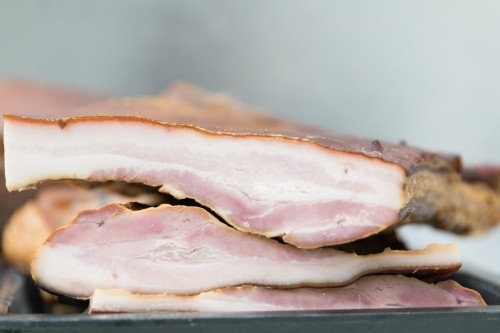 Smoked unsliced bacon on a tray in butchers shop - Australian Stock Image