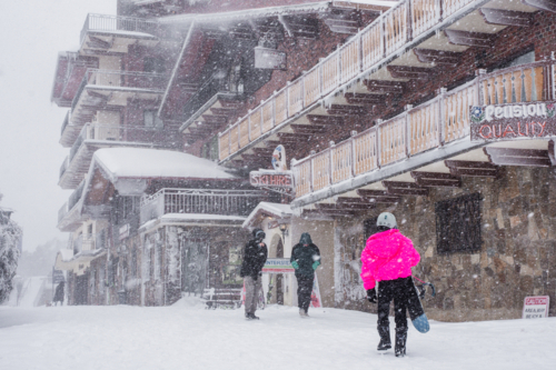 Snow boarder in pink jacket in snowy village, horizontal - Australian Stock Image
