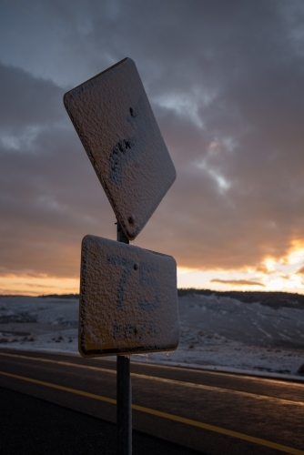 Snow covered road sign at dawn