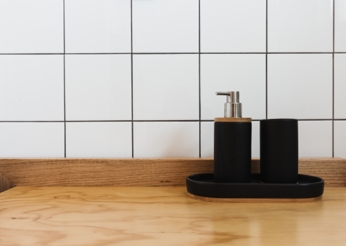 Soap dispenser and tub in black on a wooden vanity in a renovated bathroom