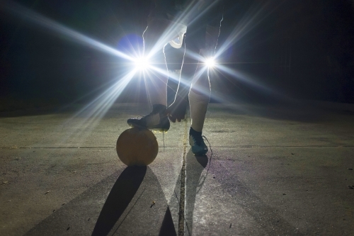 Soccer player standing in front of headlights at night