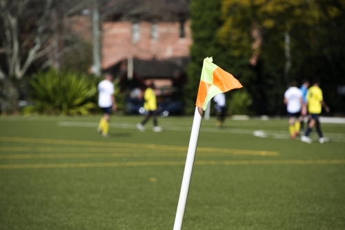 Soccer players on a field with flag in foreground - Australian Stock Image