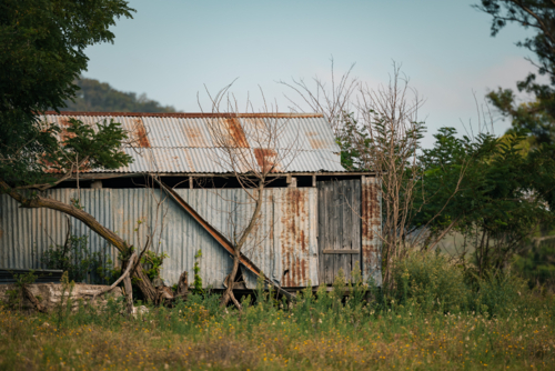 Soft blue sky over rural Australian landscape with rustic shearing shed - Australian Stock Image
