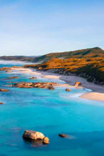 Soft evening light washes over the granite boulders and turquoise waters of Elephant Rocks - Australian Stock Image