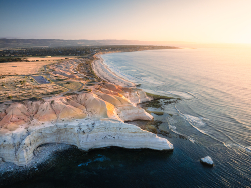 Soft golden light spills across the layered cliffs and coastline of Maslin Beach, South Australia - Australian Stock Image