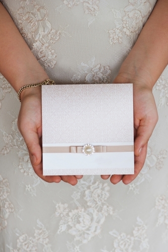 soft neutral wedding invitation being held by bride