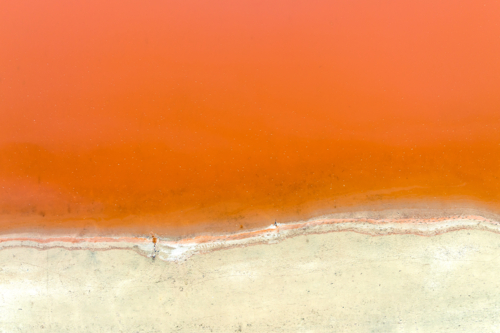 Soft orange salt lake meeting pale cracked shoreline - Australian Stock Image