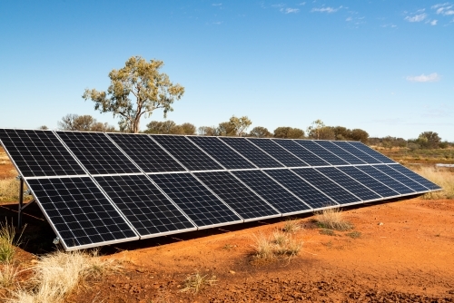 Solar Panels in desert region with cracked orange mud in foreground - Australian Stock Image