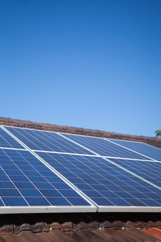 Solar panels installed on roof under blue sky - Australian Stock Image