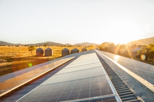 Solar panels on a shed roof generating energy with sunlight lens flare - Australian Stock Image