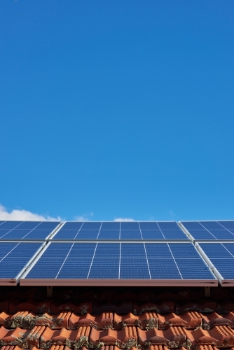 Solar panels on tile roof under blue skies