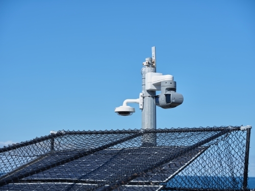 Solar panels with fences and a post with a light and camera - Australian Stock Image