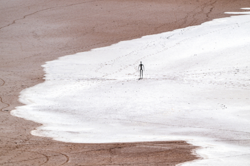 Solitary metal figure standing on a vast salt-crusted lakebed. - Australian Stock Image