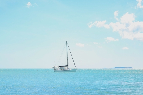 Solo yacht on calm ocean water in the Whitsundays - Australian Stock Image