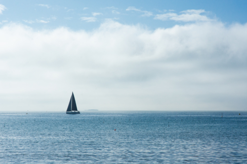 Solo yacht on calm ocean with blue sunny sky - horizontal - Australian Stock Image