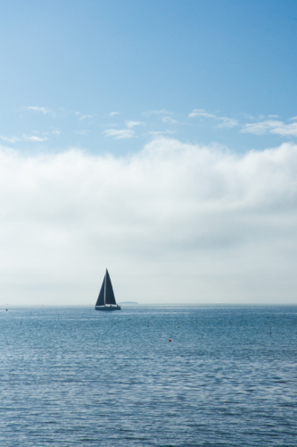 Solo yacht on calm ocean with blue sunny sky - vertical - Australian Stock Image