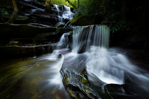 Somersby Falls, long exposure of mossy waterfall in dark green forest