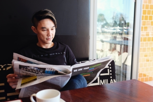 Southeast Asian multicultural man reading paper - Australian Stock Image