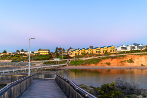 Southport boardwalk towards the surf life saving club across the Onkaparinga river at sunset - Australian Stock Image