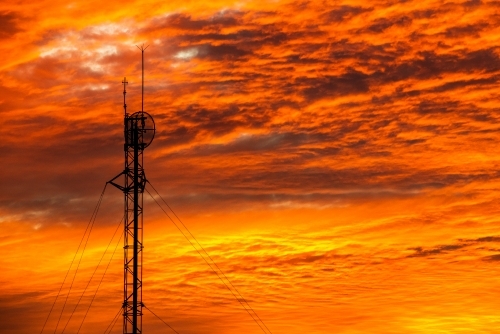 Spectacular orange sunset sky with communications tower silhouette.