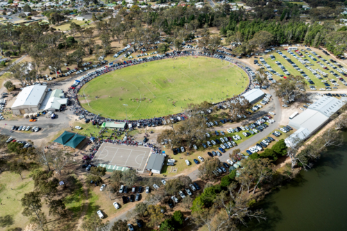 Spectators and players at a country football ground on a clear day - Australian Stock Image